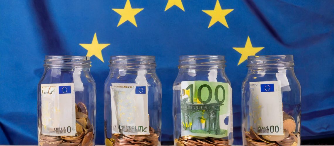 Firefly vier glazen potten vol met euro's op een tafel met op de achtergrond de blauwe vlag van de E